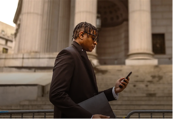 Man looking at his phone while walking in front of a government building