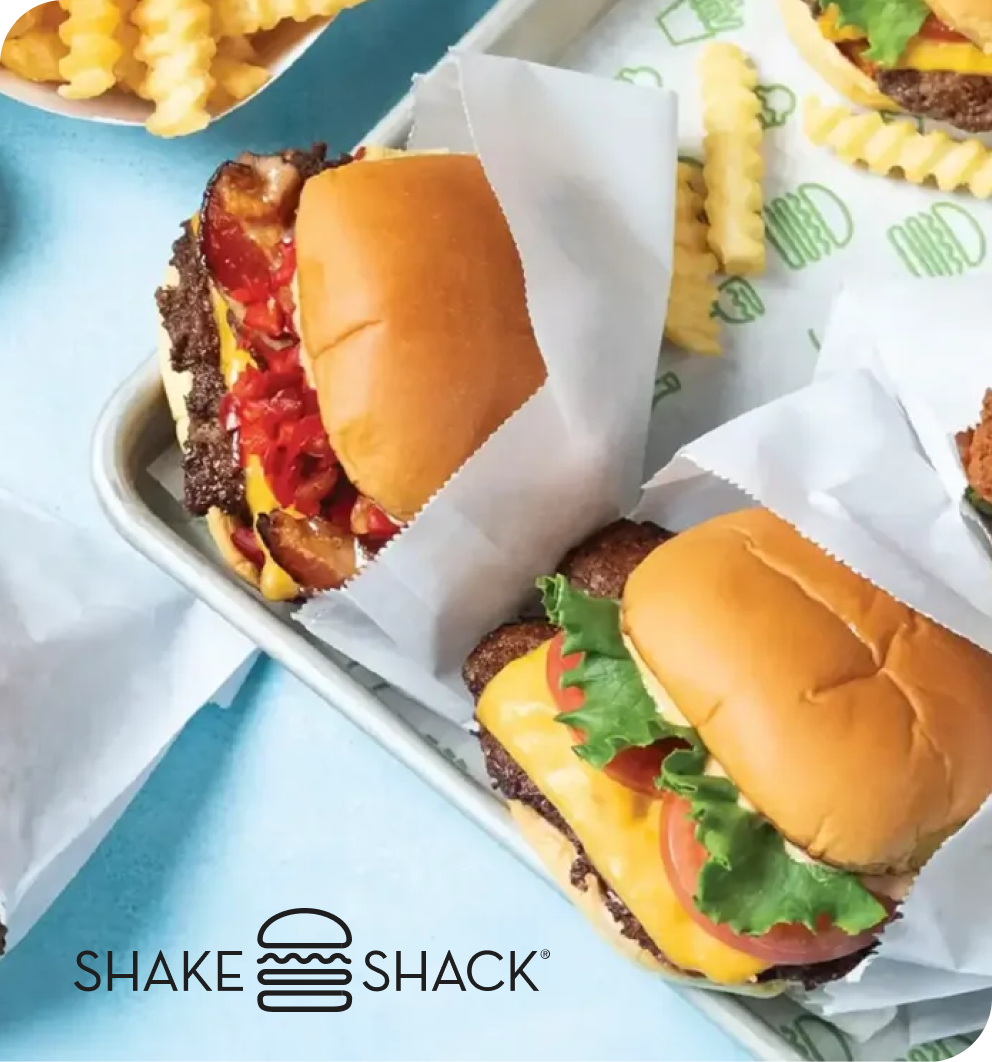 Shake Shack burgers and crinkle-cut fries served on a tray with branded greaseproof paper.